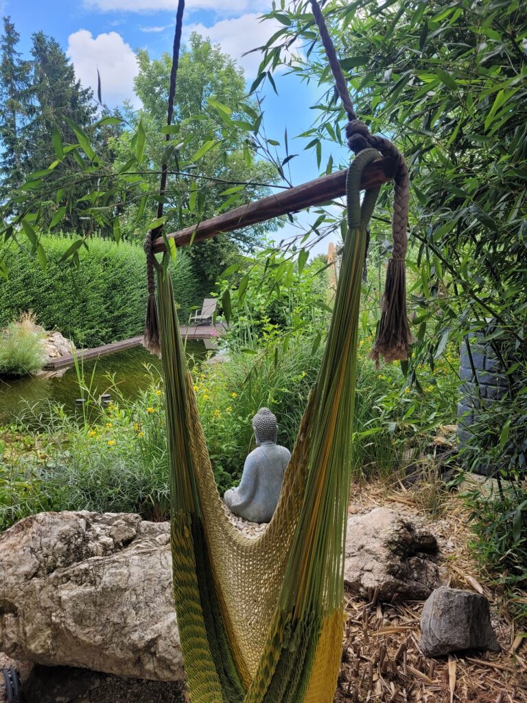 Hängesessel und Buddhastatue vor dem Biotop beim privaten Yoga Retreat