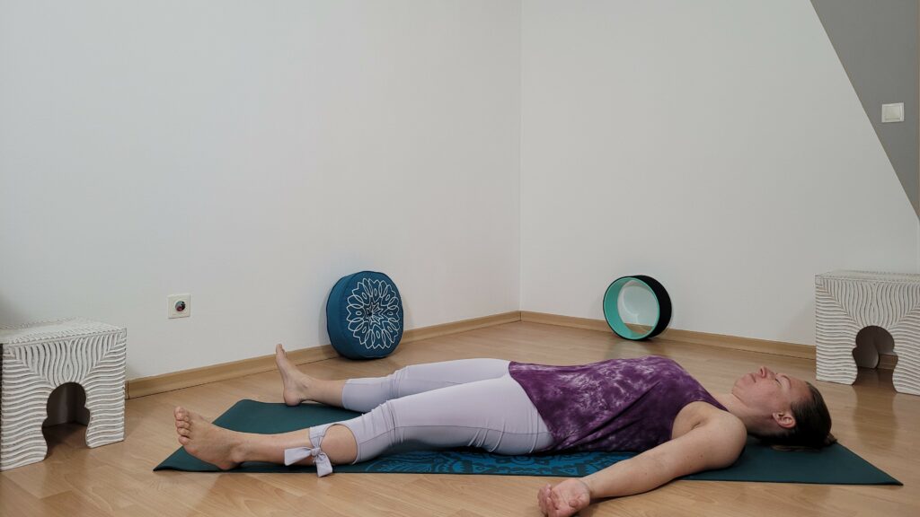 Yogini in Rückenlage führt Atem Übung für besseren Schlaf durch