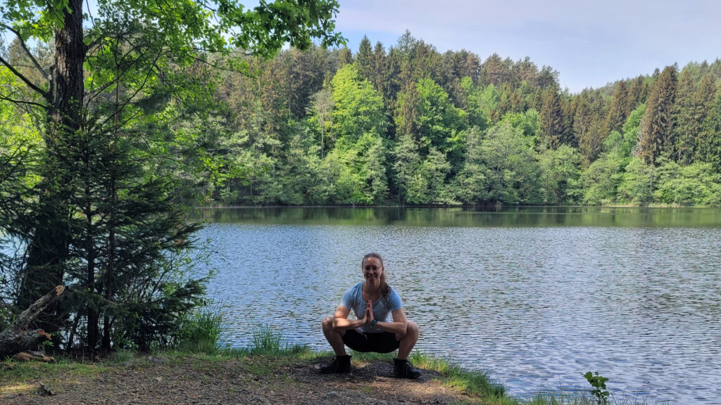 Yogalehrerin in der Hocke vor einem Teich