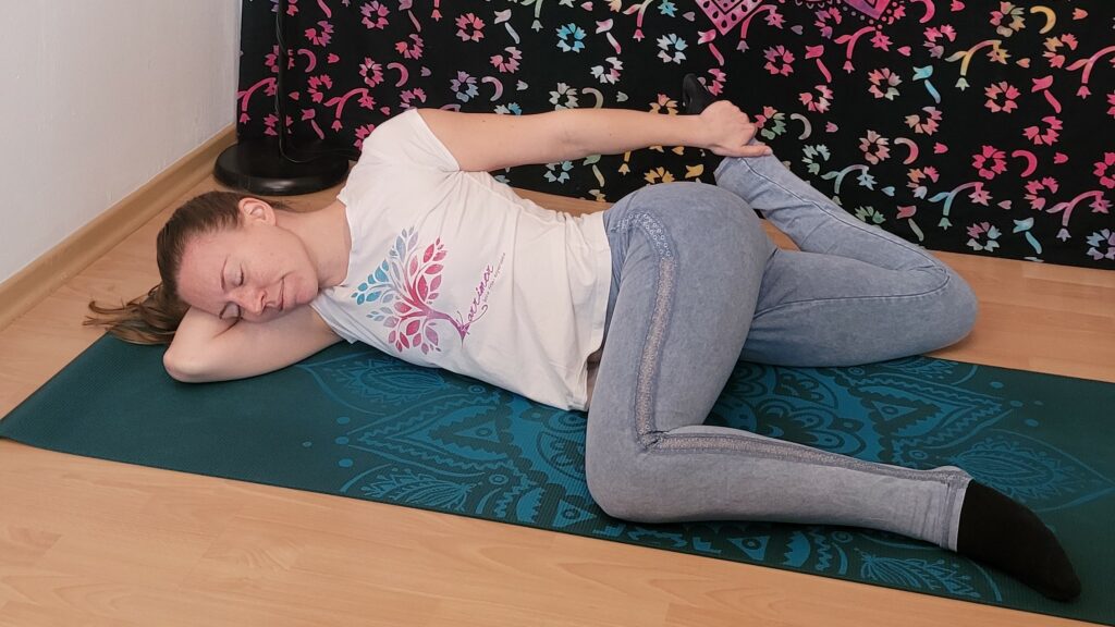 Frau in liegender Katze als Beispiel für Yin Yoga im Sommer