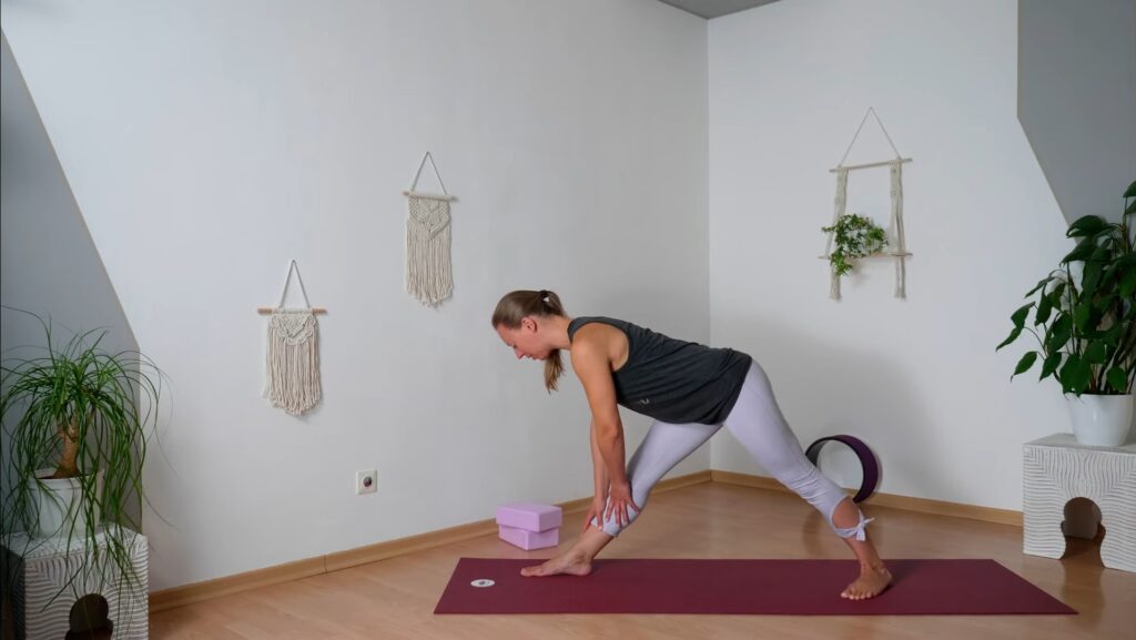 Yogalehrerin im Home Studio zeigt mit der Pyramide eine passive Dehnübung für die Beine