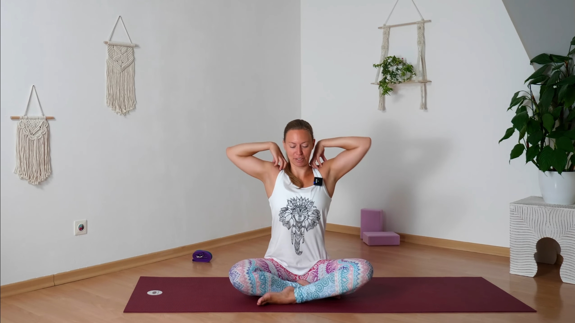 Yogalehrerin kreist ihre Schultern, die Fingerspitzen auf den Schultern