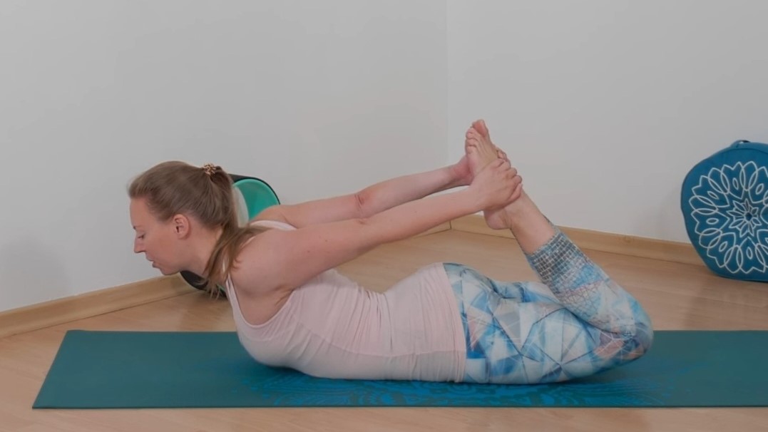 Frau in pastellfarbenem Yogaoutfit übt den Bogen