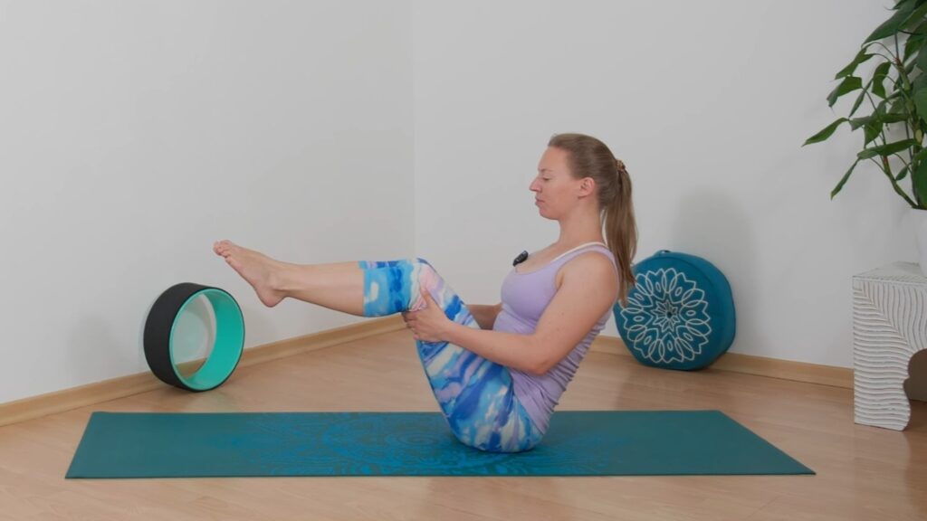 Yogalehrerin zeigt Übung zur Kräftigung von Bauch und Rücken