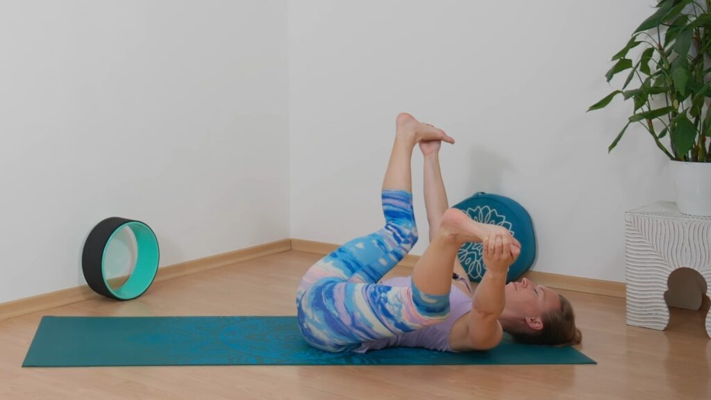 Yogalehrerin Sabrina Farkas in Rückenlage, die Hände an den Füßen