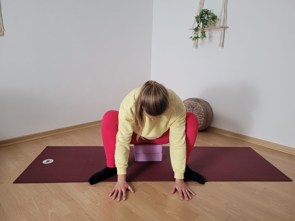 Frau in hockender Position auf Yogablöcken beim Yin Yoga für den Winter