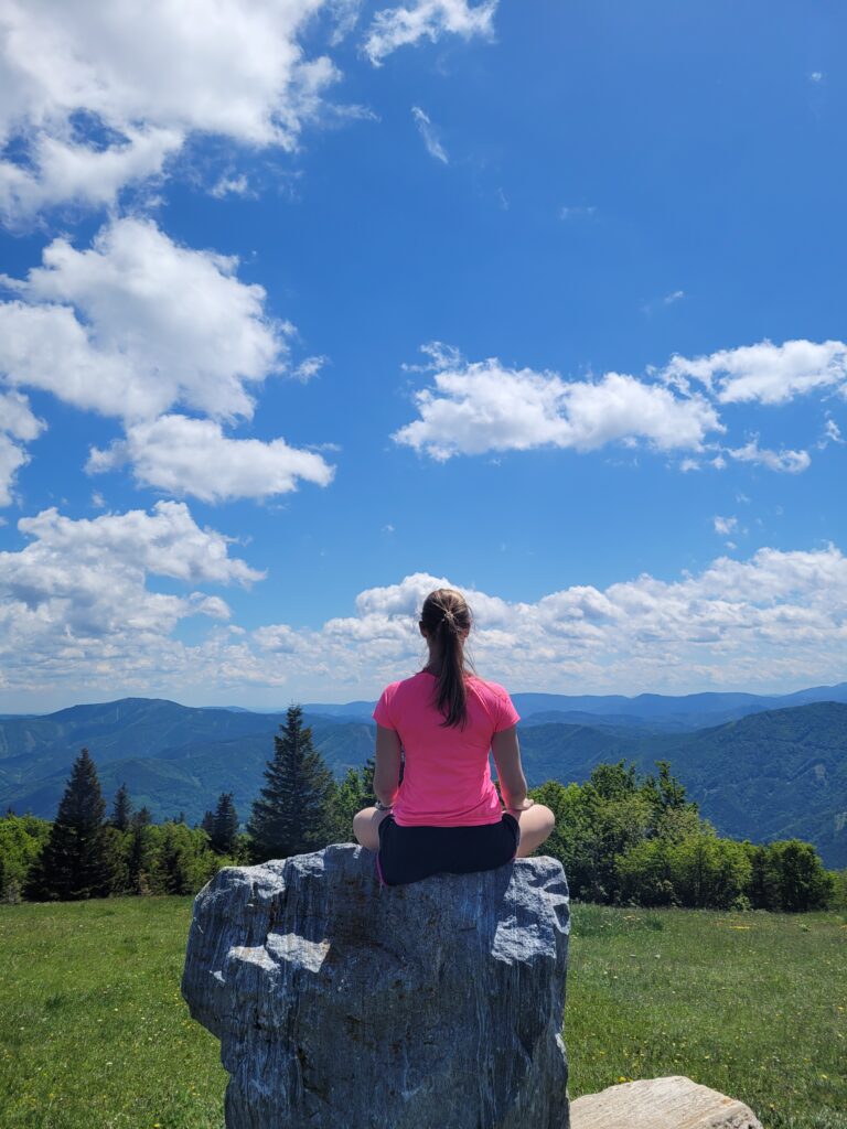 Frau im Gebirge meditiert auf Felsen