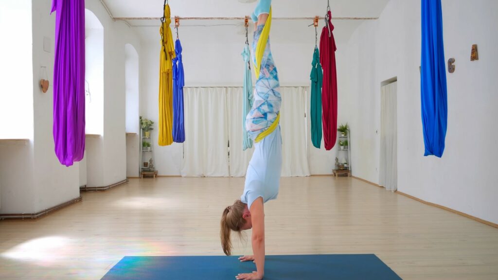 Yogalehrerin Sabrina praktiziert den Handstand mit Hilfe eines Tuches, das sie um Beine und Hüfte geschlungen hat