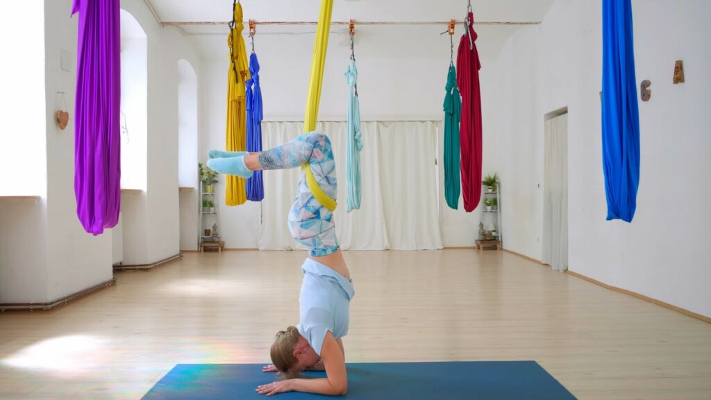 Bunte Aerial Yoga Tücher in einem Studio, Sabrina zeigt den Unterarmstand mit den Beinen in einem Tuch