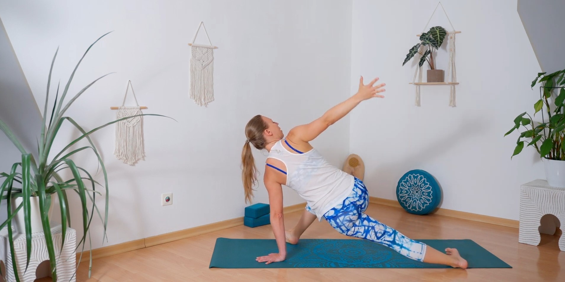 Frau in Yoga Montur dehnt in Schrittstellung ihre Hüfte beim online Functional Yoga, eine Hand auf die Matte gestützt