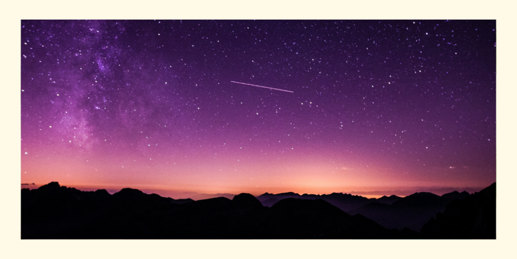 Nächtlicher Sternenhimmel über dunkler Gebirgskette mit Sternschnuppe als Titelbild der ersten Fly & Flow Spotify Meditation