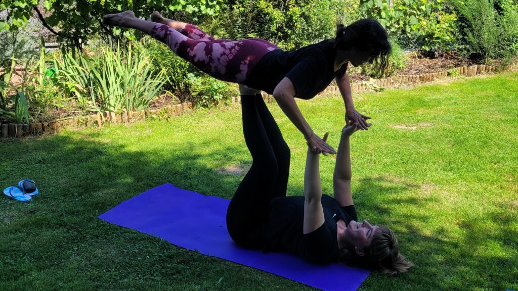 Weibliches Acro Yoga Duo übt den Bird auf einer No Name Yogamatte