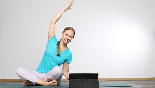 Online Yogalehrerin in sitzender Seitbeuge vor dem Tablet