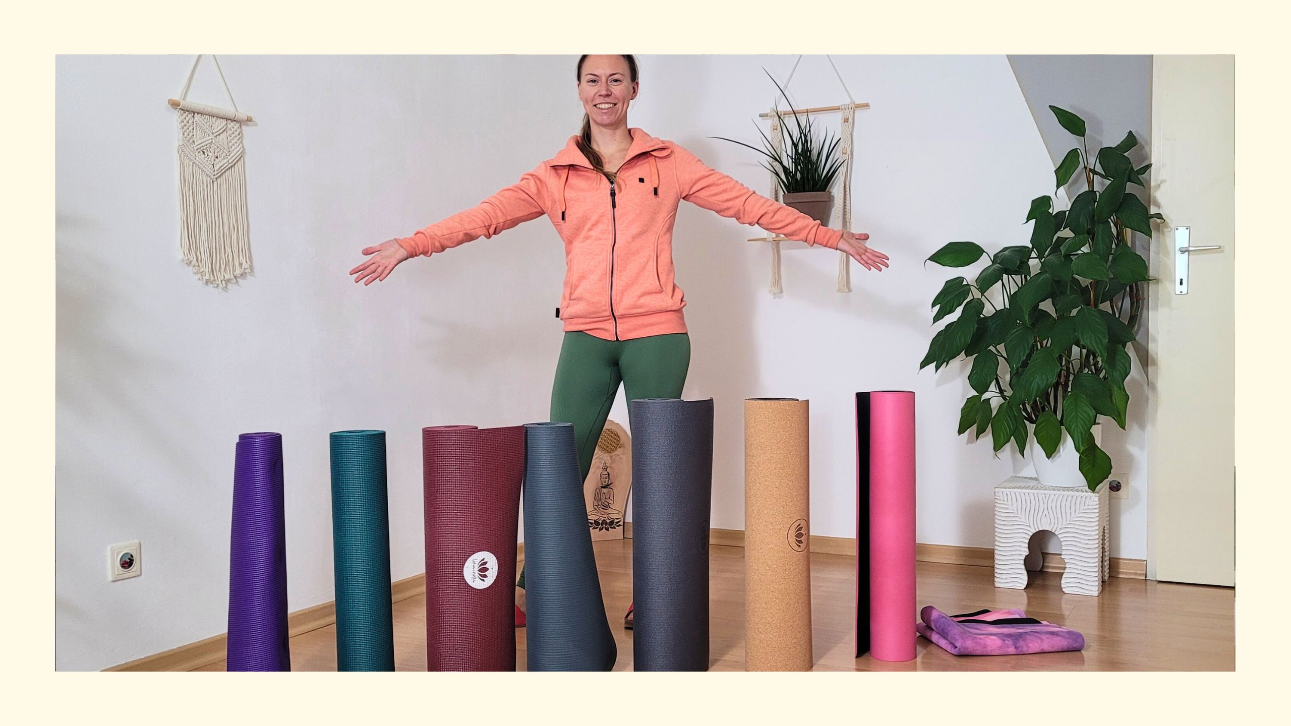 Sabrina lächelt mit ausgebreiteten Armen, vor ihr acht Yogamatten aufgereiht für den Test, welche die beste Yogamatte 2025 ist