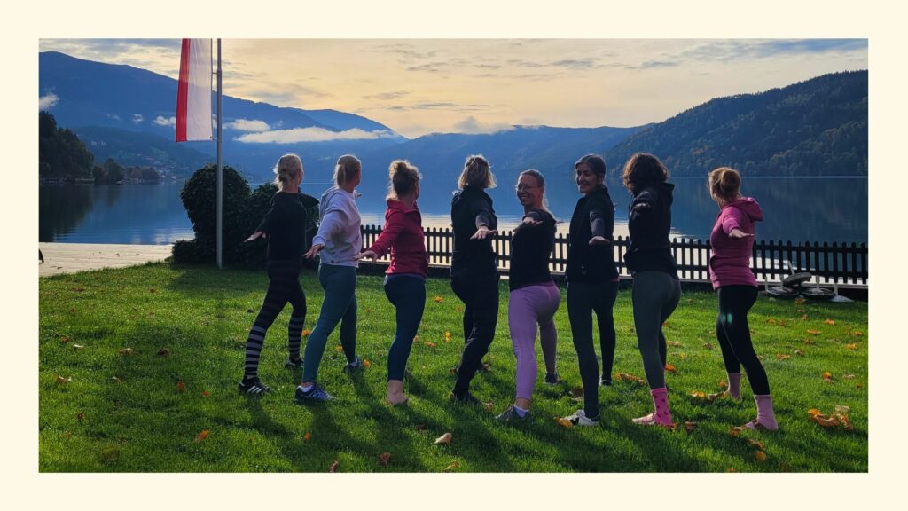 Foto einer Gruppe Frauen im Krieger 2 am Millstätter See zur Motivation für die Planung deines 1. Yoga Retreats