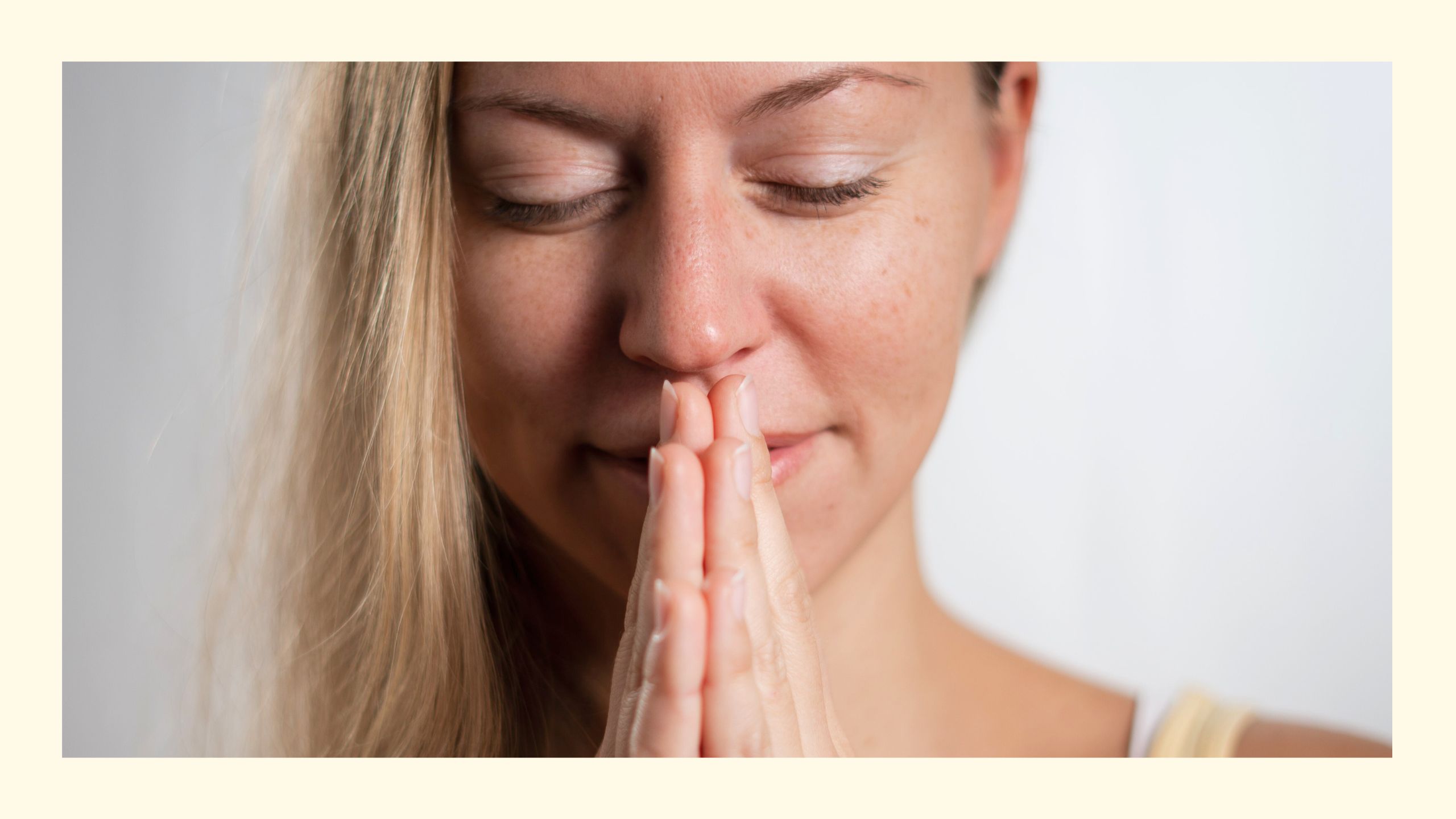 Portrait von Yogalehrerin Sabrina lächelnd mit geschlossenen Augen und Händen in Gebetshaltung, die Finger an den Lippen bei den 108 Sonnengrüßen zur Wintersonnenwende in Wien