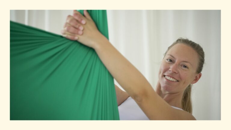 Nach hinten gelehnte, lächelnde Lehrerin im Tuch bei der Aerial Yoga Lehrer Ausbildung in Wien, Österreich